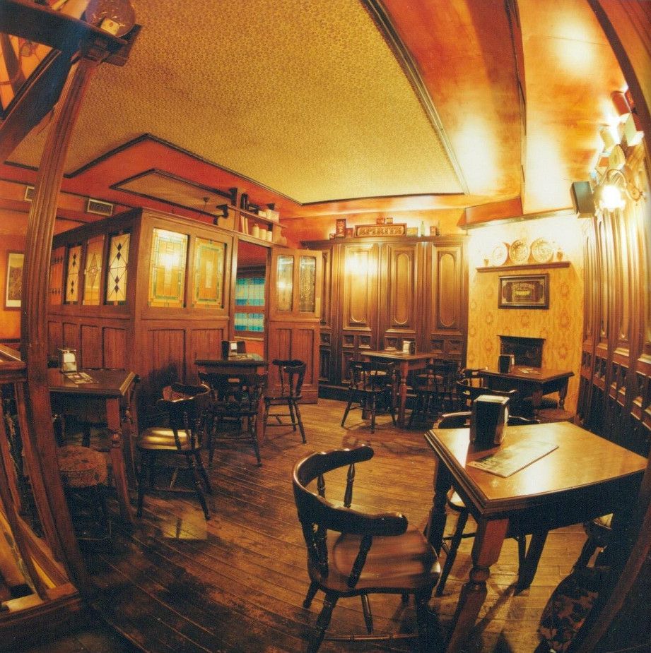 Sala interna in legno con camino, tavoli tondi e boiserie.